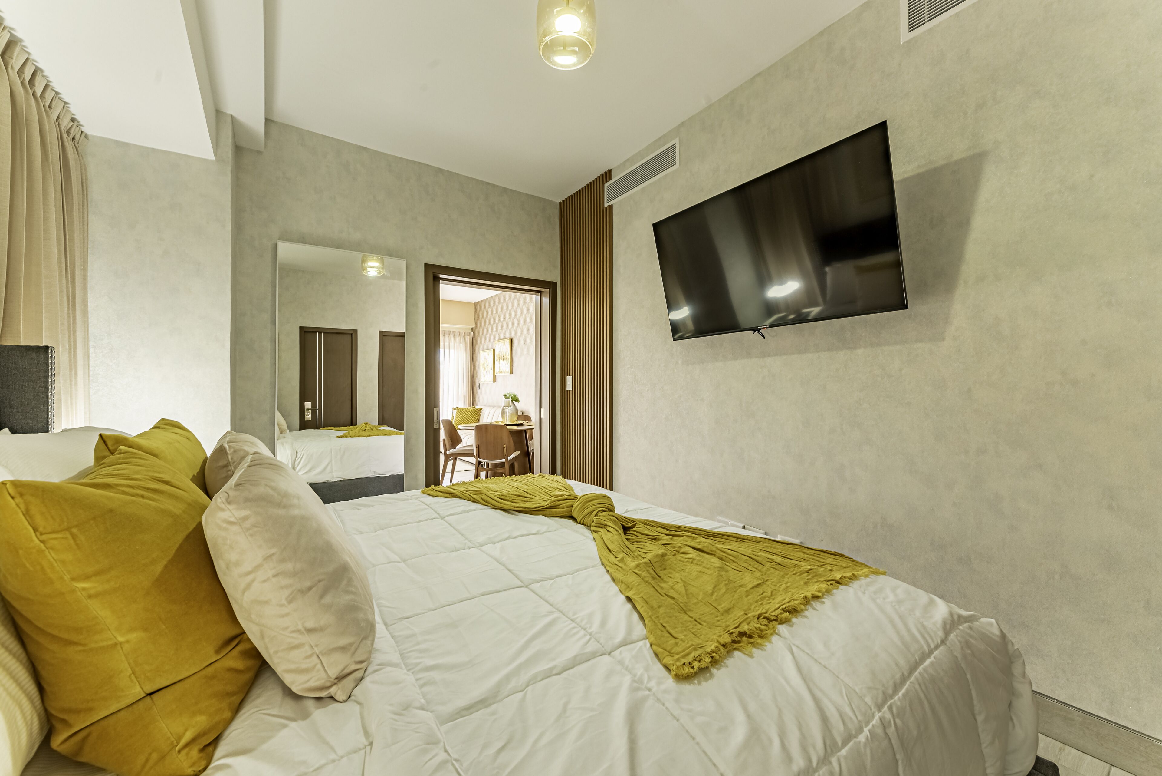 Een hotelkamer met een bed, een aan de muur bevestigde televisie en een deur naar een badkamer.