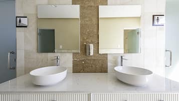 Une salle de bain moderne avec deux lavabos, un grand miroir et un porte-serviettes.