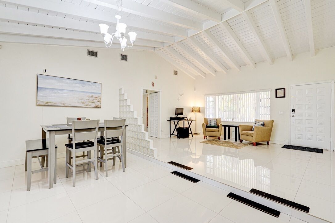 A spacious living area with a dining table and chairs, a sofa, a lamp, and a painting on the wall.