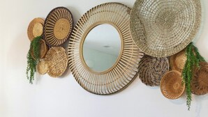 Un sofá modular con un espejo y cestas tejidas en la pared.