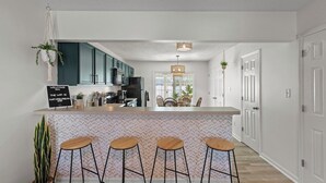 Una cocina moderna con barra, que incluye un cartel, taburetes y plantas en macetas.