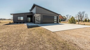 Une maison moderne à deux étages, dotée d’un garage, d’une grande allée et d’un terrain de basketball.