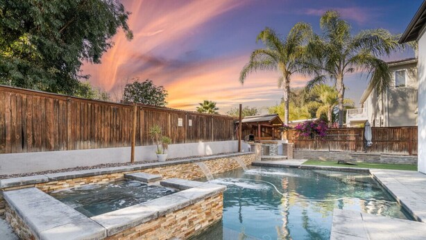 Un patio trasero con piscina, cerca de madera y una casa.