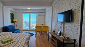 Une chambre d’hôtel moderne avec deux lits, un bureau avec un ordinateur, une télévision et un balcon avec des chaises jaunes.