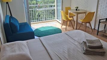 Une chambre d’hôtel avec un lit, un canapé, un balcon avec une table et des chaises, et une vue sur la mer.