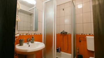 Une salle de bain équipée d’un lavabo, d’un miroir, d’une douche et de toilettes.