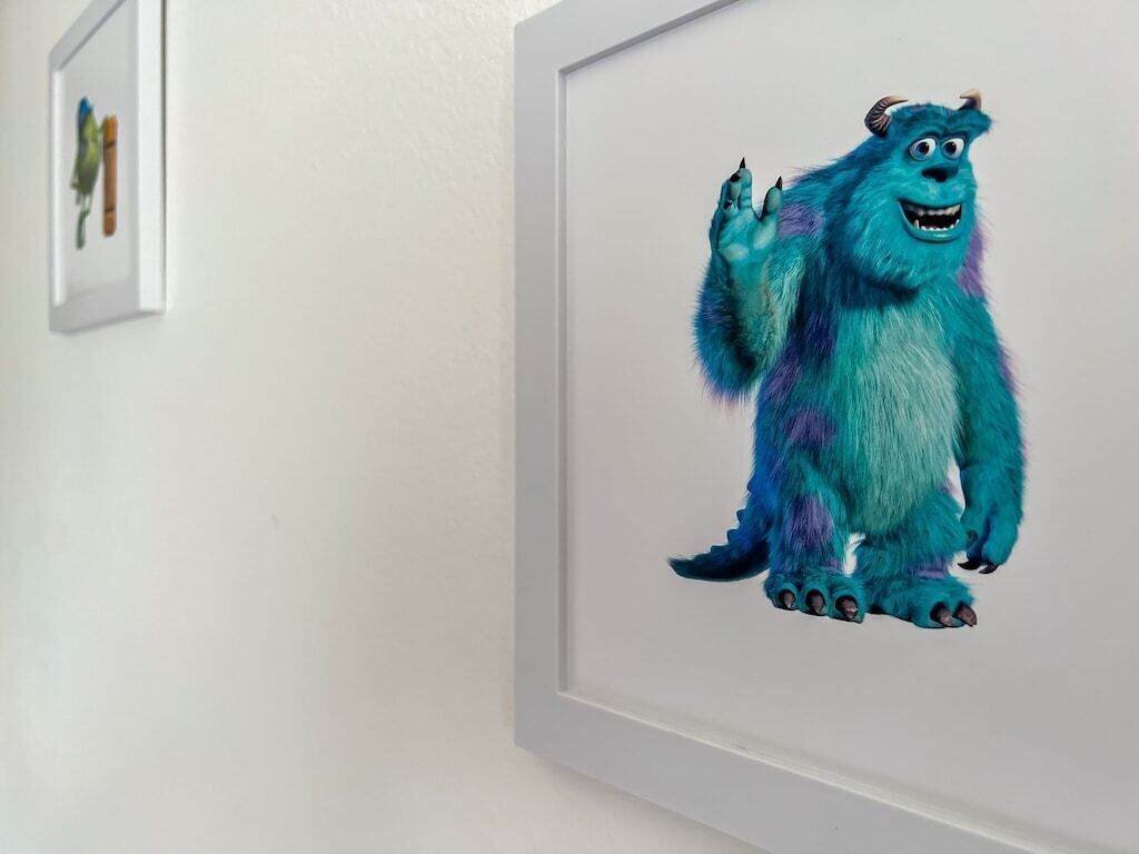 A framed picture of a blue furry character on a white wall.
