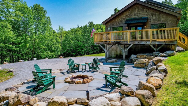 Eine Lodge mit einer Terrasse, Sitzgelegenheiten im Freien und einer Feuerstelle.