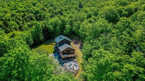Eine Lodge, umgeben von dichtem Wald, mit einer großen Terrasse und einem Sitzbereich im Freien.