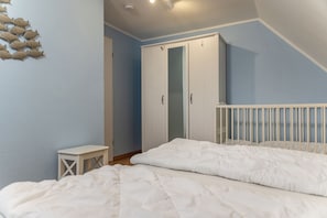 Una camera da letto con un letto, un tavolino, un armadio e una culla.