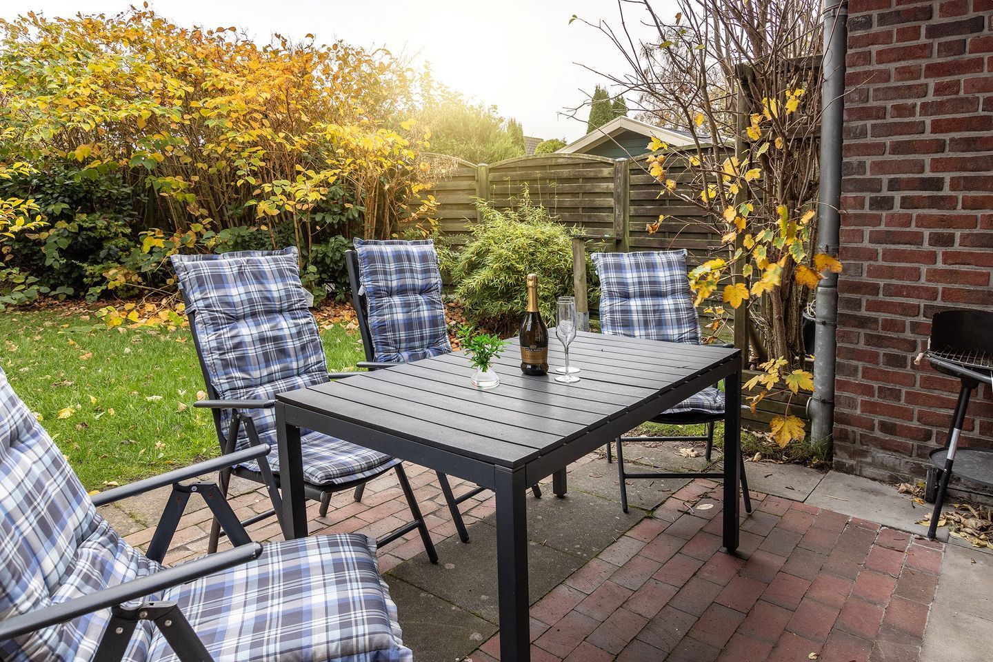 Eine Terrasse mit Tisch und Stühlen, einer Champagnerflasche und einer kleinen Pflanze.