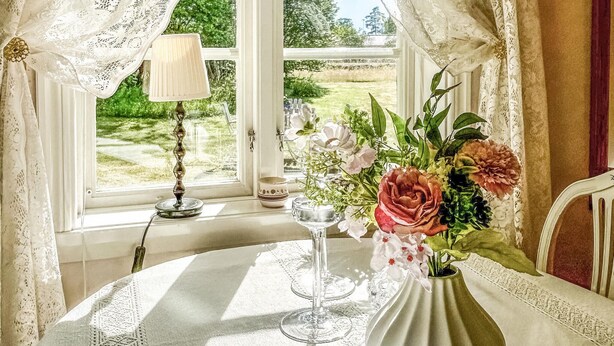 A table with a vase of flowers, a candle, and a glass.
