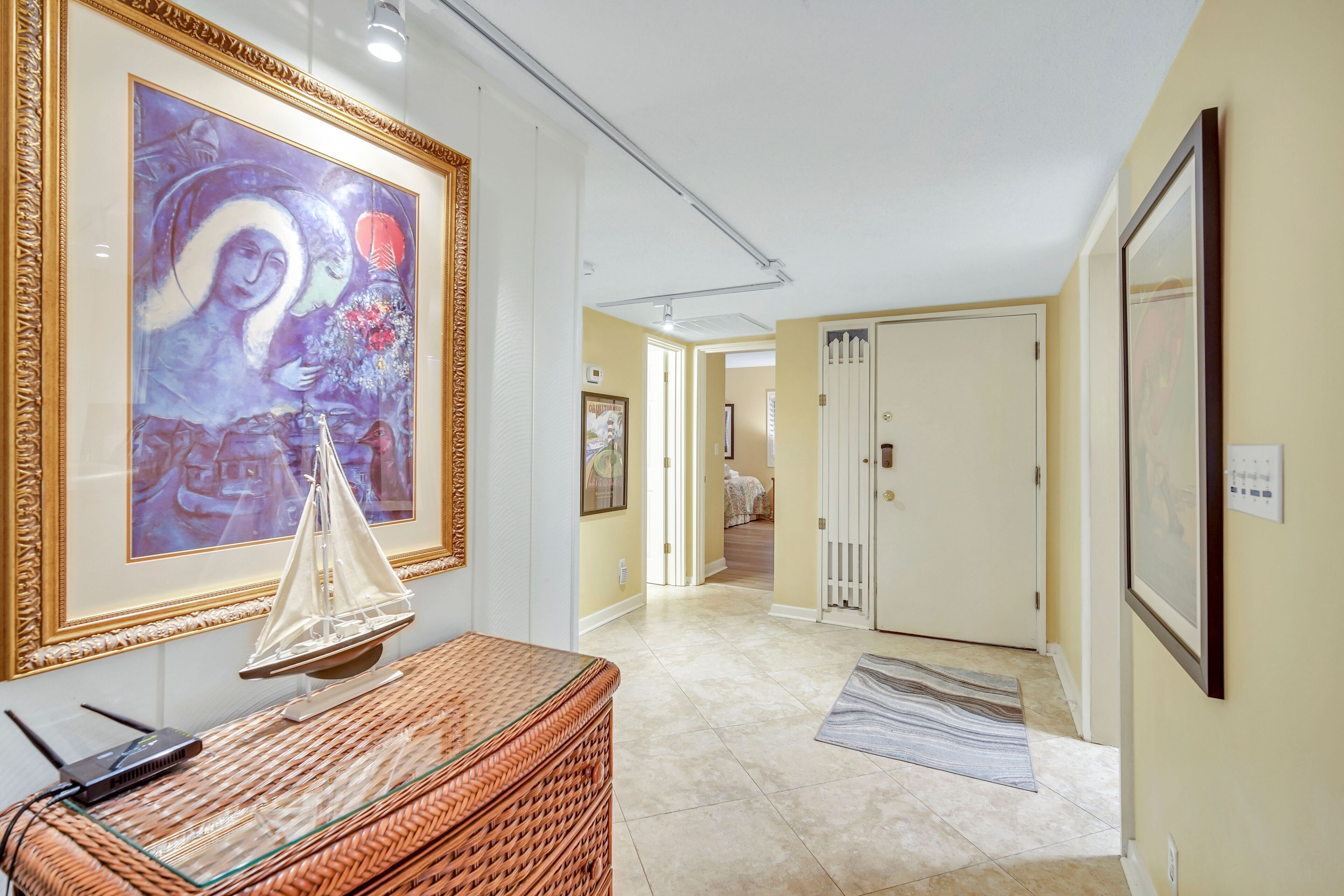 A hallway with a framed painting, a wicker basket, and a door leading to another room.