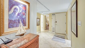 Un couloir orné d’un tableau encadré, d’un panier en osier et d’une porte donnant sur une autre pièce.