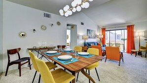 Comedor con mesa de madera dispuesta para cuatro personas, sillas amarillas y una lámpara de techo moderna.