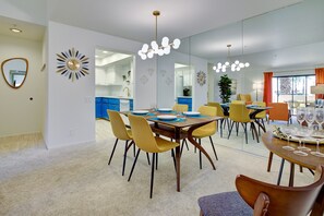 A modern dining area with a large table, yellow chairs, and a chandelier. - Mid Century Escape. Envious location. (Palm Springs)