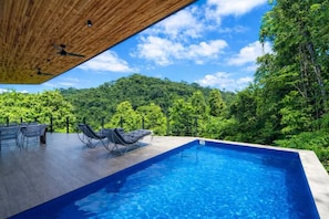 A swimming pool with lounge chairs and a wooden ceiling.