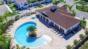 A residential area with a swimming pool, a covered patio, and a row of townhouses. - Beautiful Town Home in Gated Community With Amenities - Close to WDW (Kissimmee)