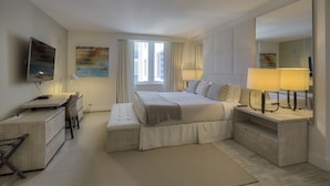 A modern hotel room with a large bed, a desk, a chair, a TV, and a large mirror.