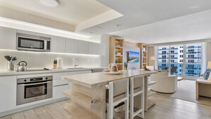 A modern kitchen with a built-in microwave, oven, and bar area with stools.