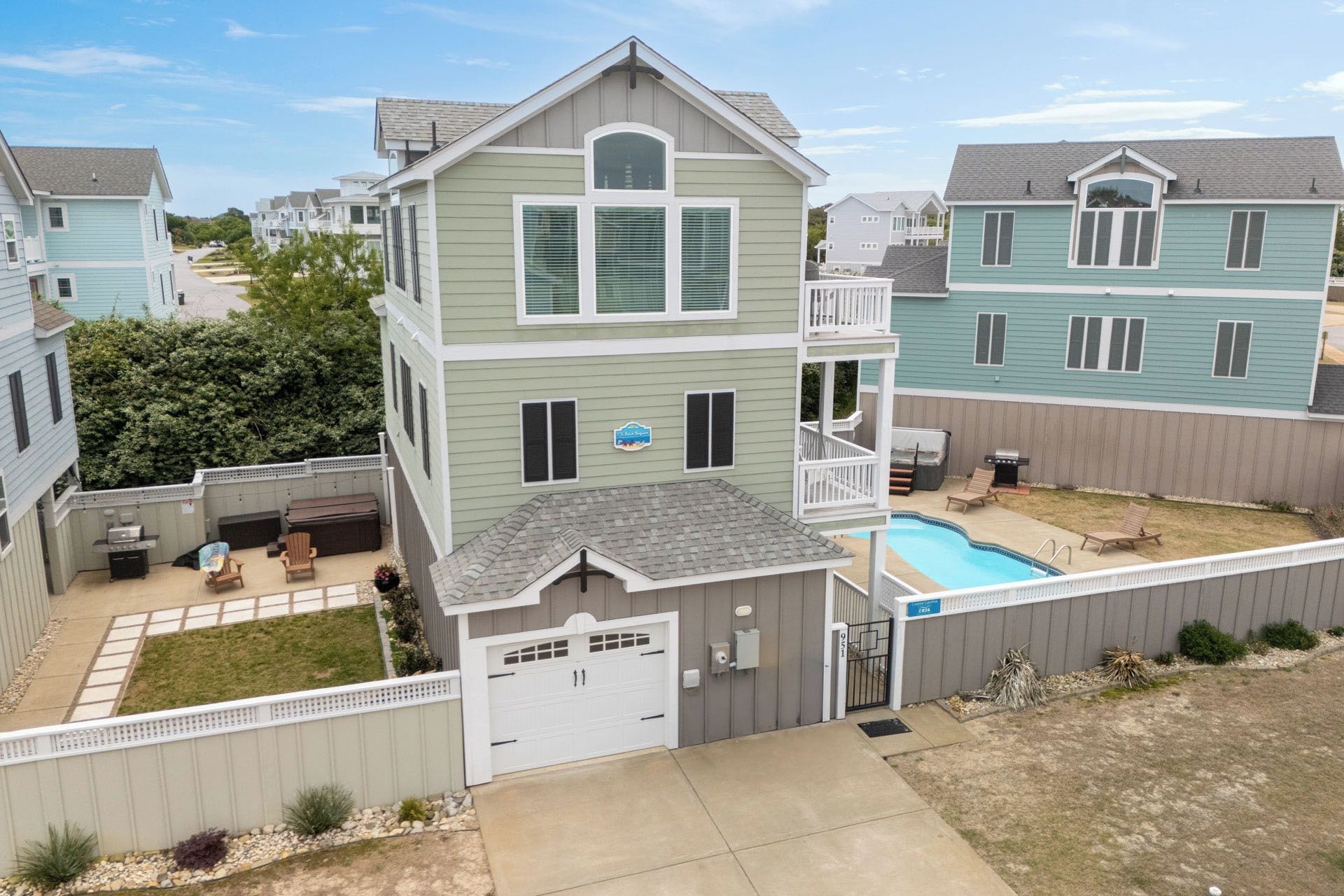 Une maison à deux étages avec une terrasse à l’avant, une piscine et un garage.