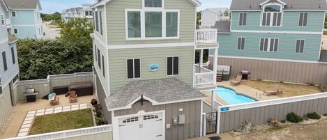 Une maison à deux étages avec une terrasse à l’avant, une piscine et un garage.