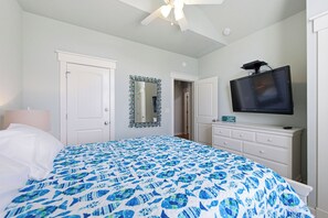 A bedroom with a bed, a television, a dresser, and a door.