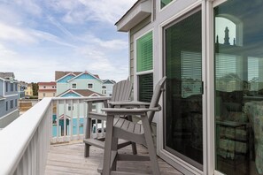A wooden deck with a chair, a large window, and a view of colorful houses.