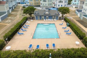 A swimming pool with lounge chairs and a small building with a sign.