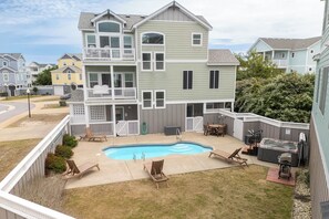 A two-story house with a backyard swimming pool, a hot tub, and a barbecue area.