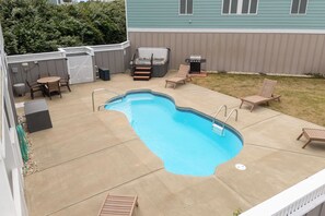 A backyard with a swimming pool, patio furniture, and a barbecue grill.