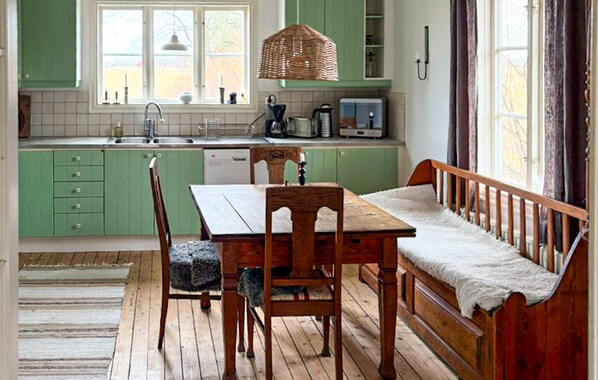 Una cocina con armarios verdes, una mesa de comedor de madera, un banco y una ventana con vistas.