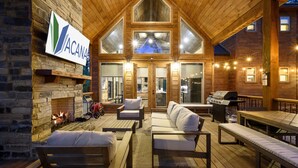 A log cabin with a stone fireplace, wooden furniture, and a grill area. - Game Room, Hot Tub, Fire Pit, Pets, High Horse (Broken Bow)