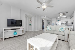 A modern living room with a flat-screen TV, white furniture, and ceiling fans. - Island Princess 404 * Beach Chair Set Included ~ Gulf Front! (Fort Walton Beach)