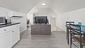 Une cuisine moderne avec des armoires blanches, un four à micro-ondes encastré et un grand îlot central.