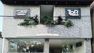 Fachada de un edificio con letreros de 'Coca-Cola' y 'TPR' en el nivel superior, y puertas de vidrio en el nivel inferior.