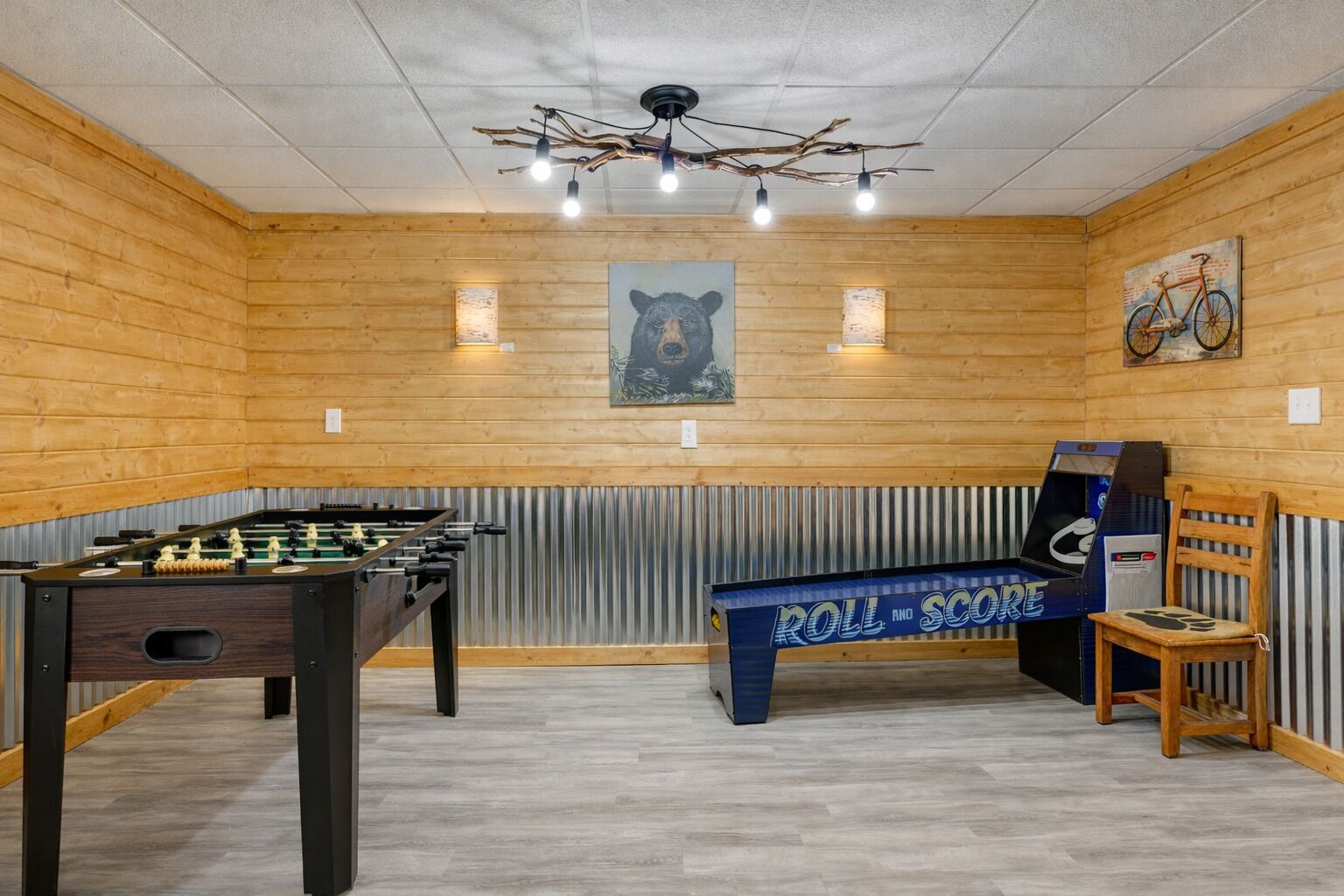 Une pièce aux murs en bois, avec un baby-foot, un banc et un tableau représentant un ours, accroché au mur.