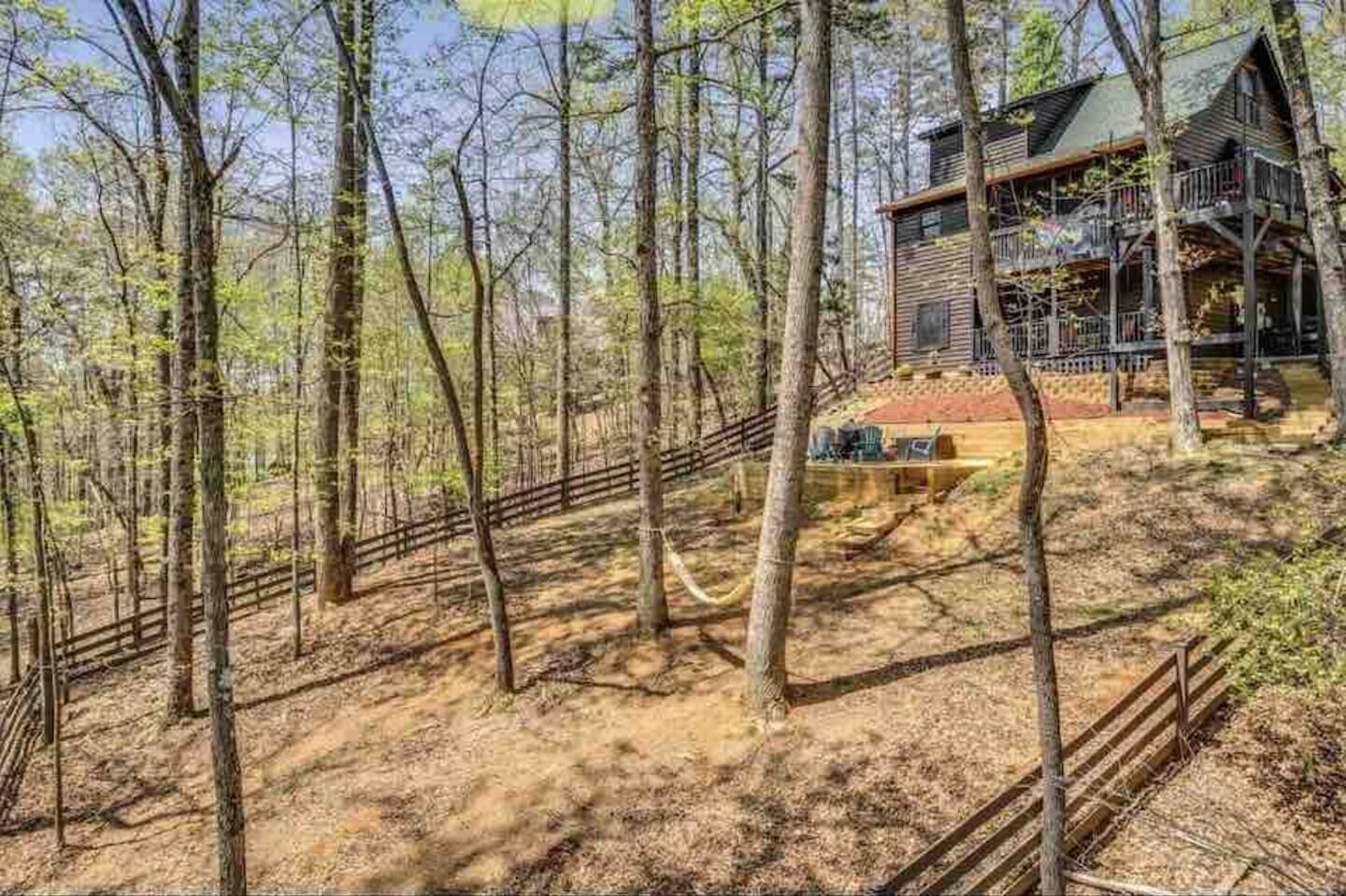 A cabin with a wooden deck and a staircase leading up to it, surrounded by a forest.