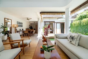 Un salon moderne comprenant un canapé, des fauteuils, une table basse et un coin repas.