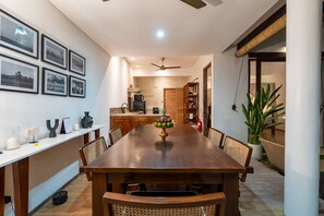 A dining area with a wooden table, chairs, a fruit centerpiece, and framed pictures on the wall.