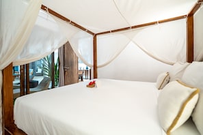 Quarto com uma cama grande, cortinas brancas e vista para o exterior.