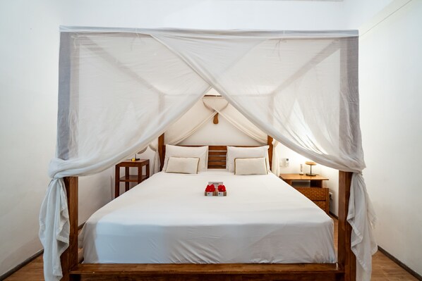 Una cama con dosel, cabecera de madera y mesitas de noche.