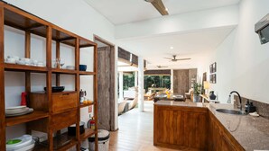 Una cocina moderna con estantes de madera, una isla central y vistas a una sala de estar.