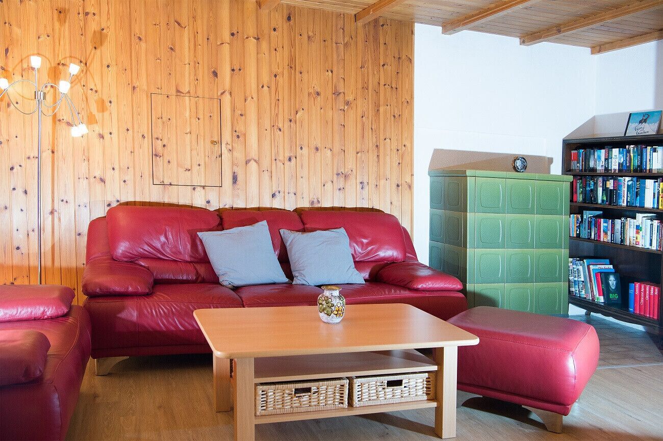 Une pièce chaleureuse avec un canapé en cuir rouge, une table basse en bois et un meuble de rangement vert.