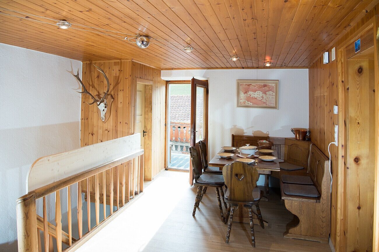Een houten interieur met een eethoek, houten wanden en een trap.