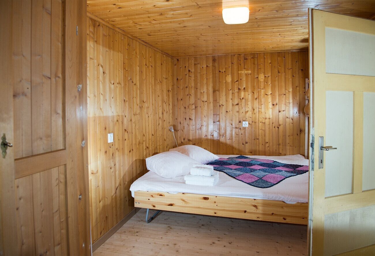 Una habitación con paneles de madera, una cama individual, un edredón y una puerta.