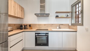 A modern kitchen with white cabinetry, a built-in oven, a sink, and wooden countertops. - Jardines - Avago 2.2 POOL VIEW 1B (Arona)