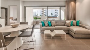 A modern living room with a sectional sofa, a round dining table, and a minimalist coffee table. - Jardines - Avago 2.2 POOL VIEW 1B (Arona)