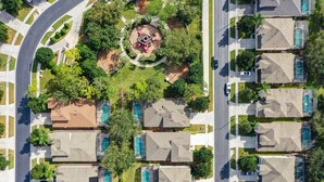 Un quartier résidentiel comprenant plusieurs maisons, un parc circulaire central et une piscine.