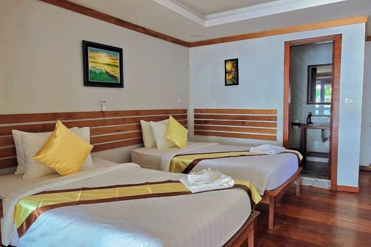 Una habitación de hotel con dos camas, cabeceros de madera y una puerta que da al baño.